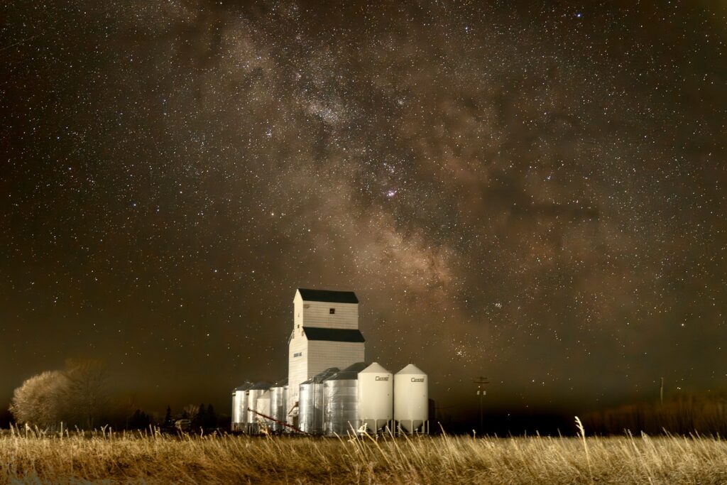 The Milky Way spread across the sky behind an abandoned grain elevator.