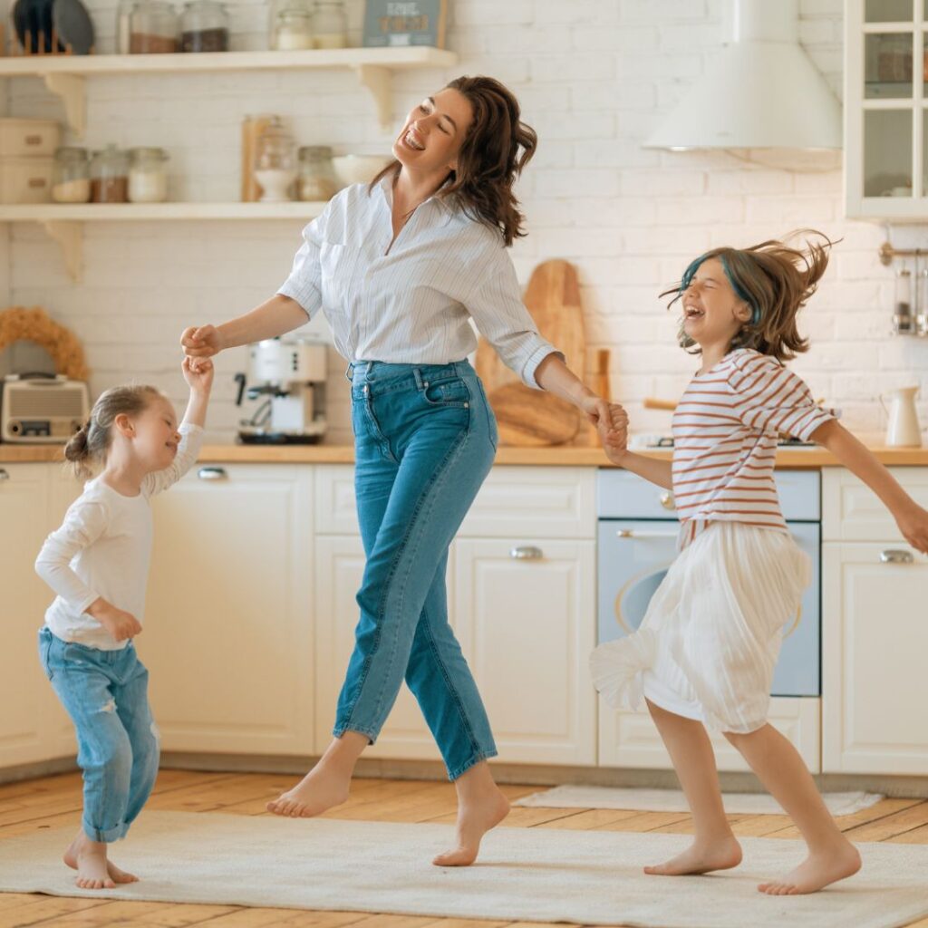 Mother with two young daughters dancing in the kitchen