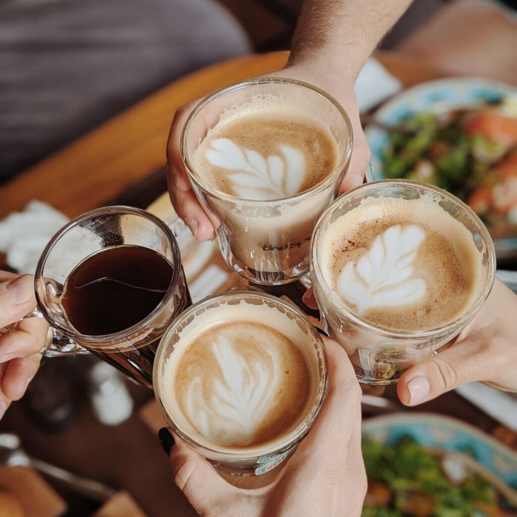 Four cups of artisan coffee cups being clinking in a cheers.