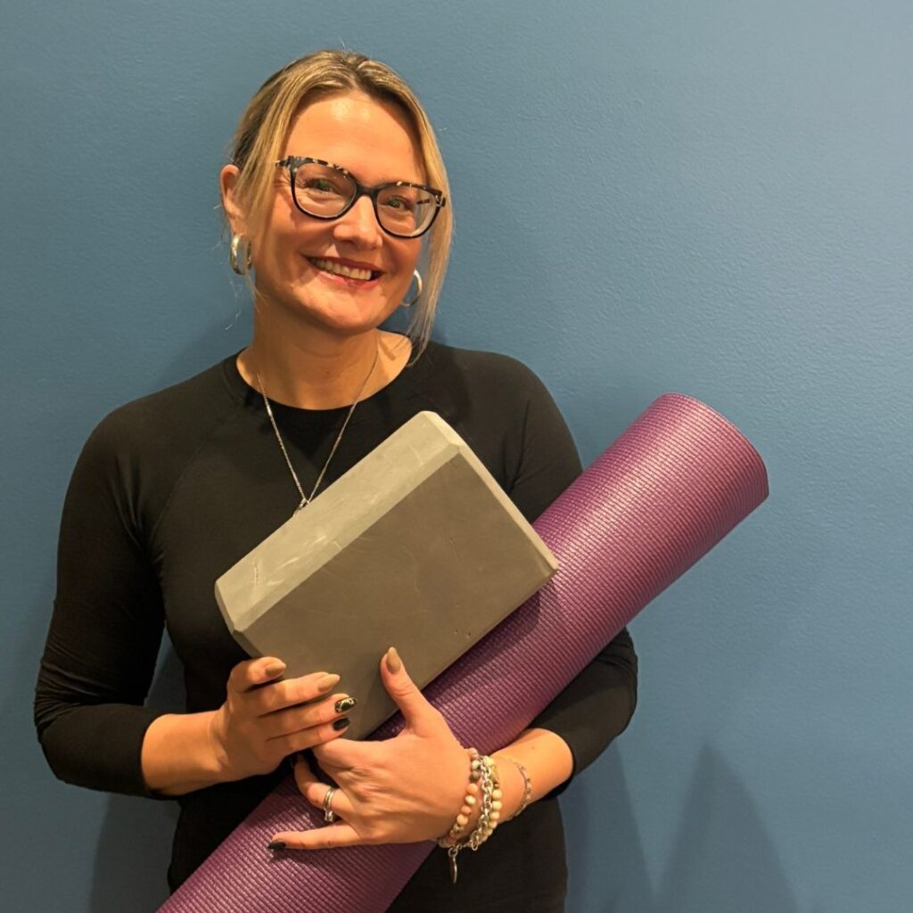 Yoga instructor Jaimie's photo holding a mat and block.