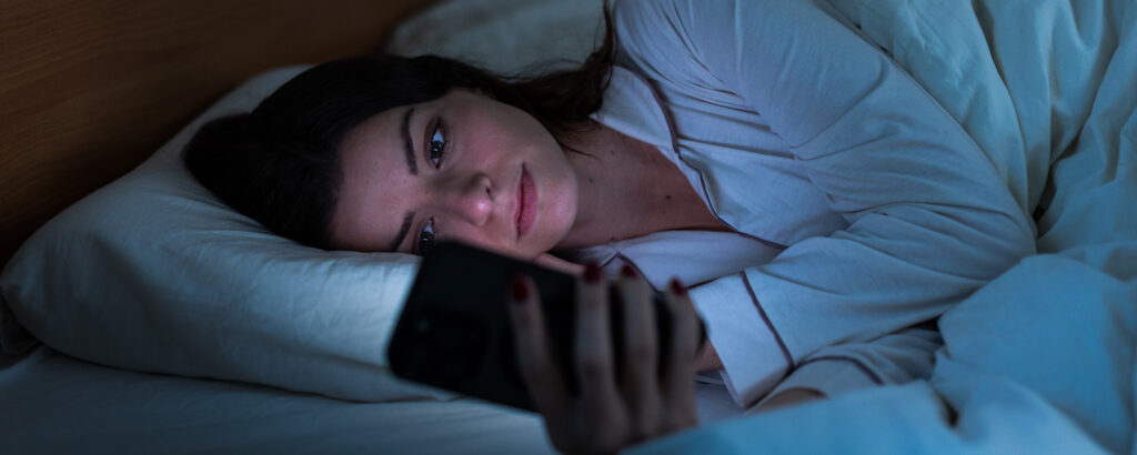 student attempting to sleep, but on phone instead. 