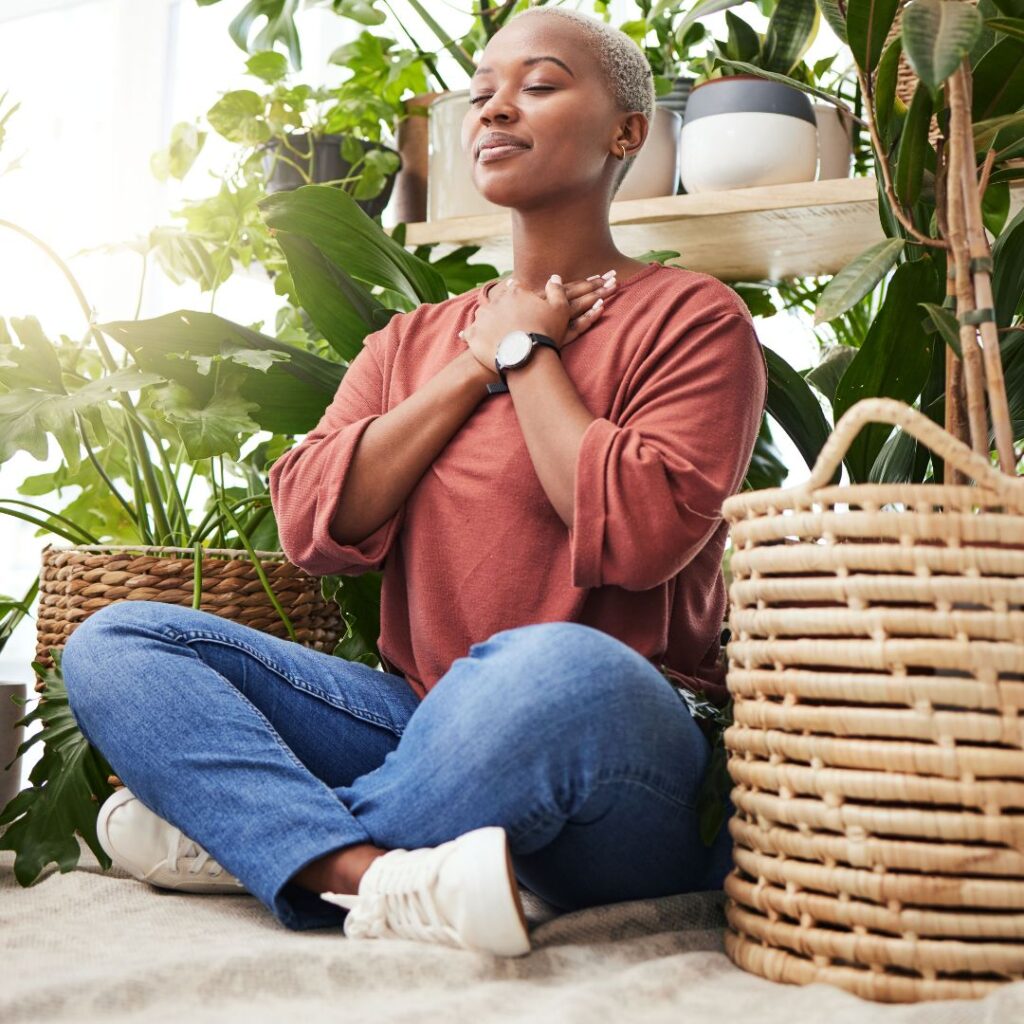 Woman sitting cross-legged with hands over heart, deep breathing