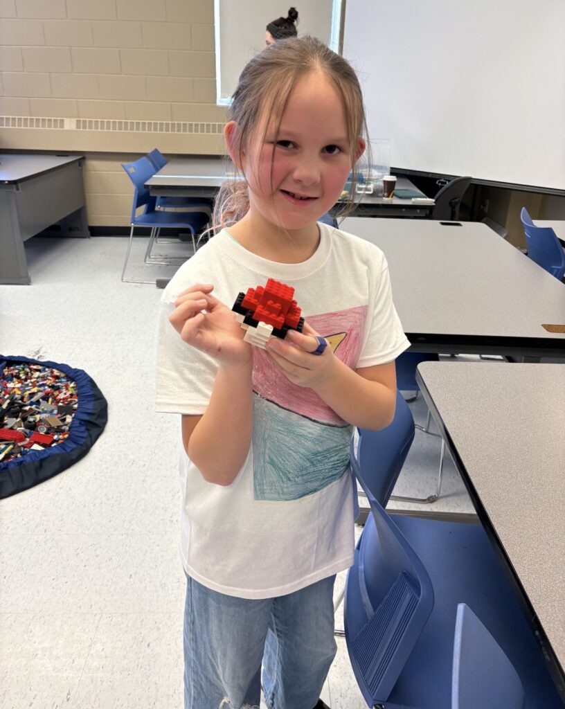 Isabella showing off her Lego creation while wearing her custom designed t-shirt