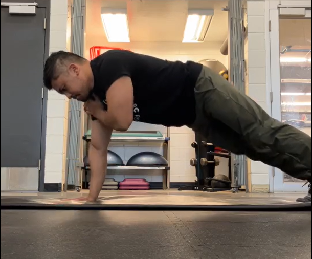 Henry demonstrating a high plank with alternating shoulder taps.