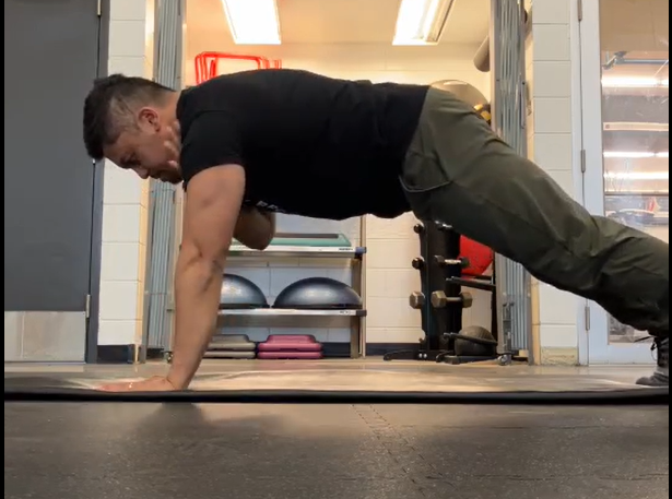 Henry demonstrating a high plank with alternating shoulder taps.