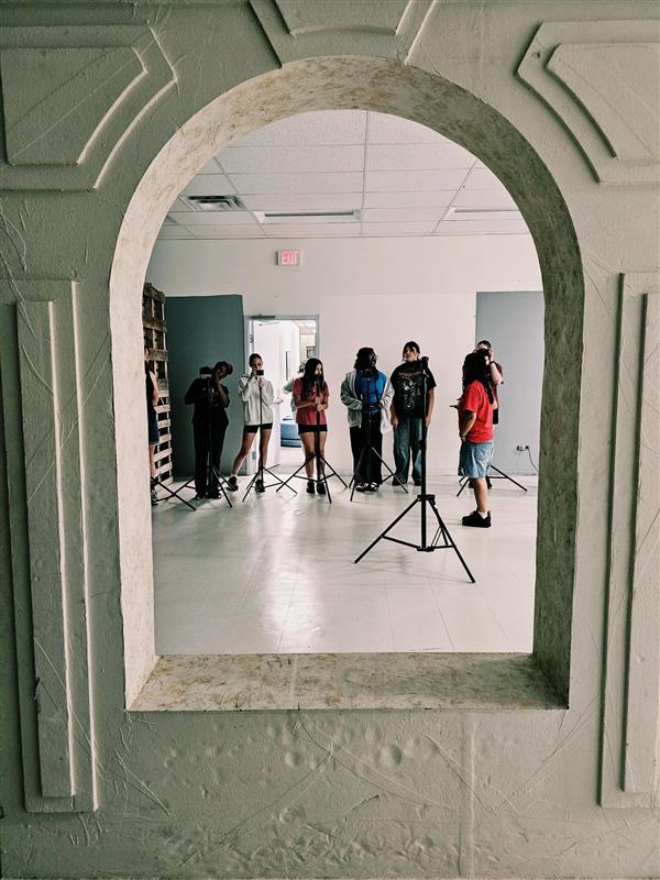 A group of campers are aiming their DSLR cameras at a rounded framed set piece