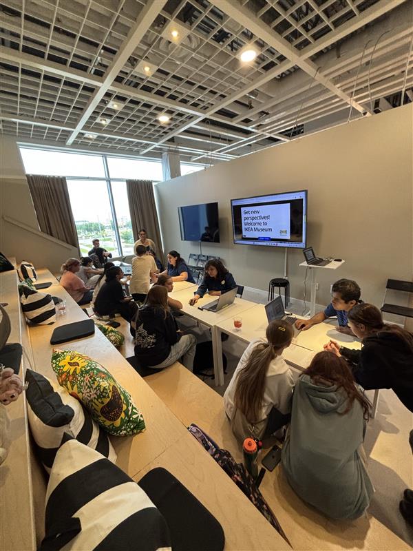 A group of campers sit in rows at IKEA while they work on laptops to design their dream rooms