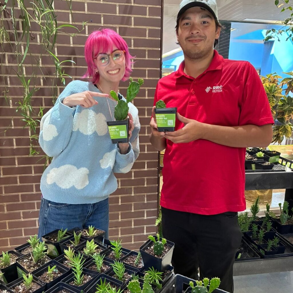 Two students holding up succulent plants.
