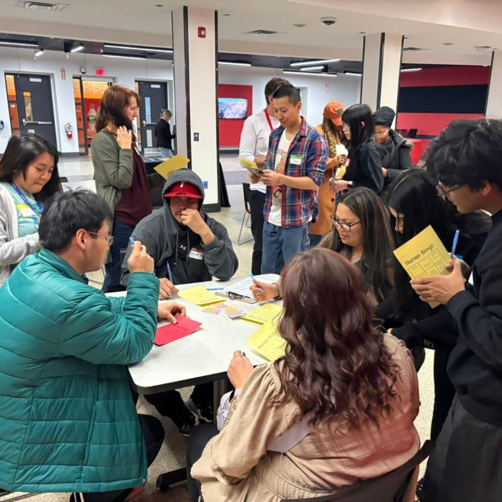 Group of students gathered around a table mingling.