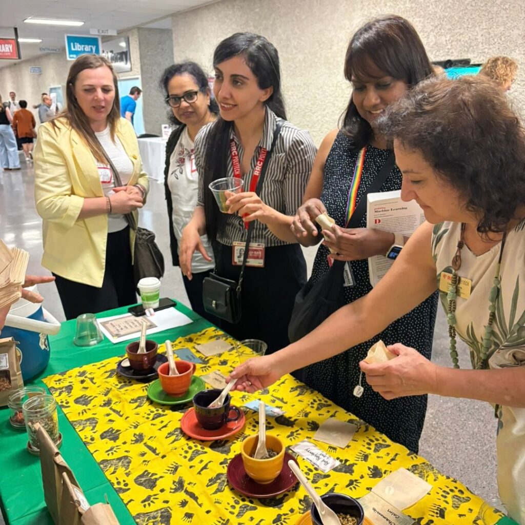 Group of people sampling tea at a display table.
