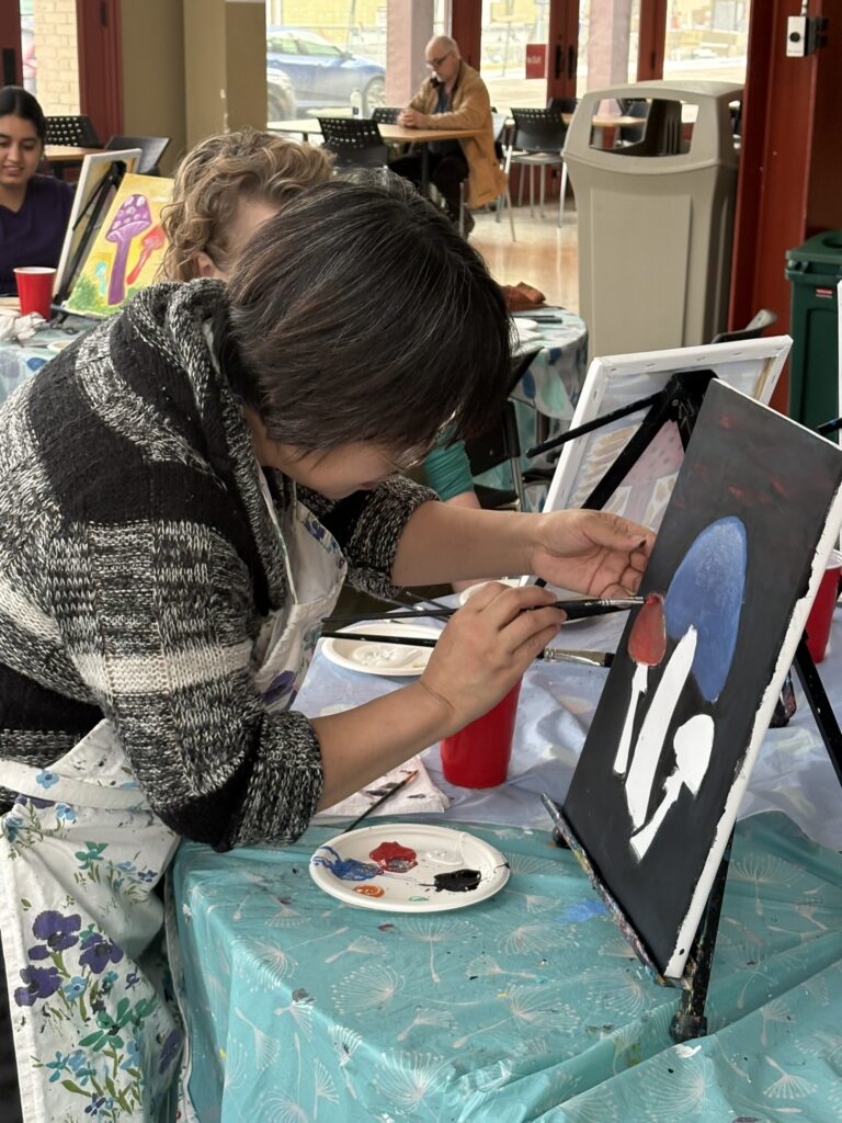 Student working on a painting of mushrooms. 