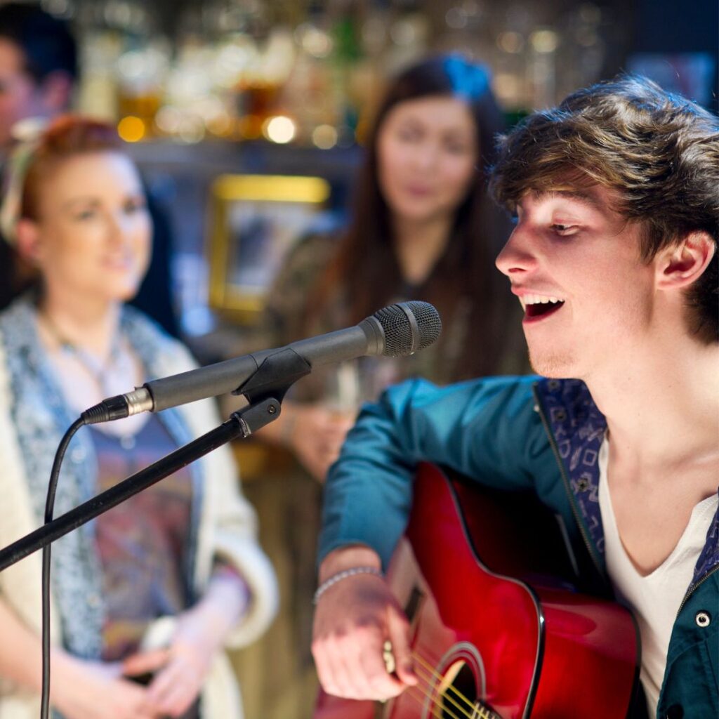 Person singing at a mic with people watching.