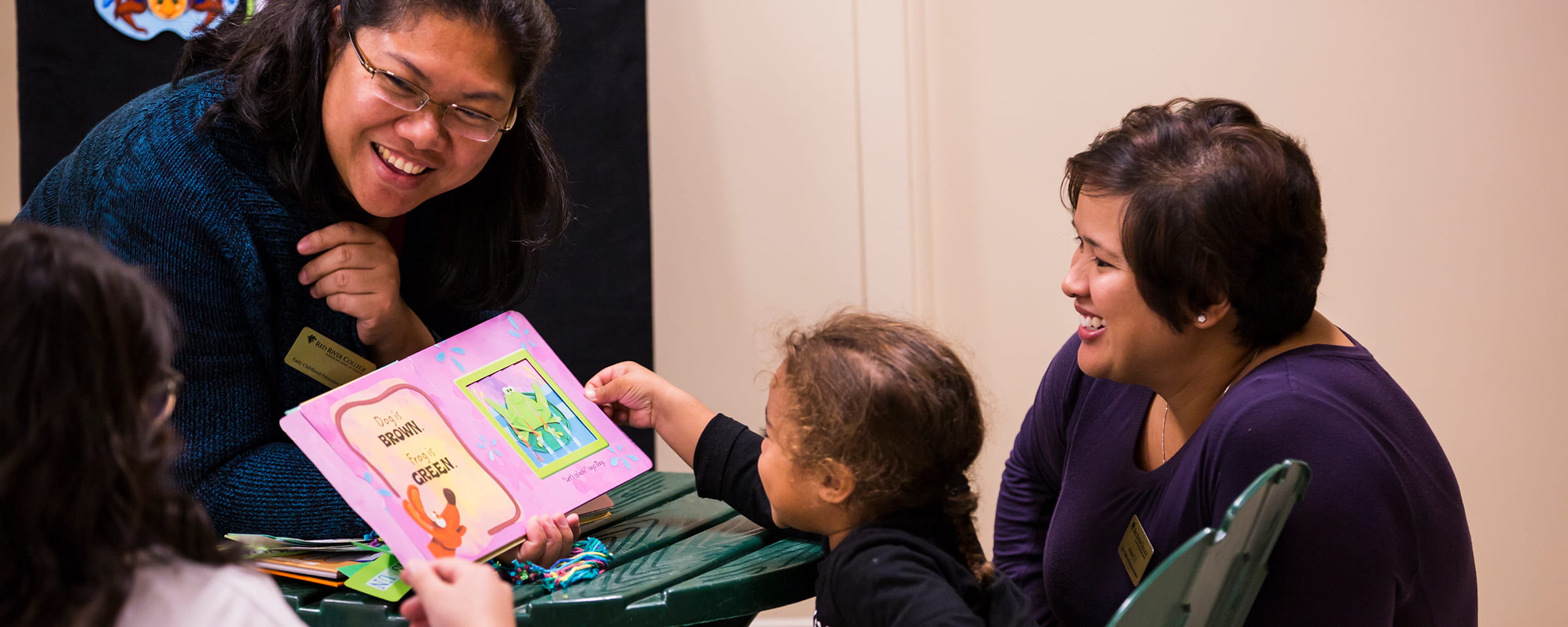 Female Early Childhood Education student reading book to child and older woman
