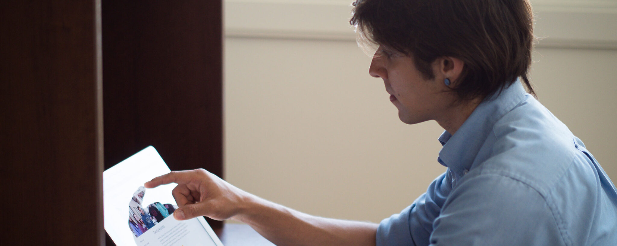 Male student touching his laptop screen going through the application process. 