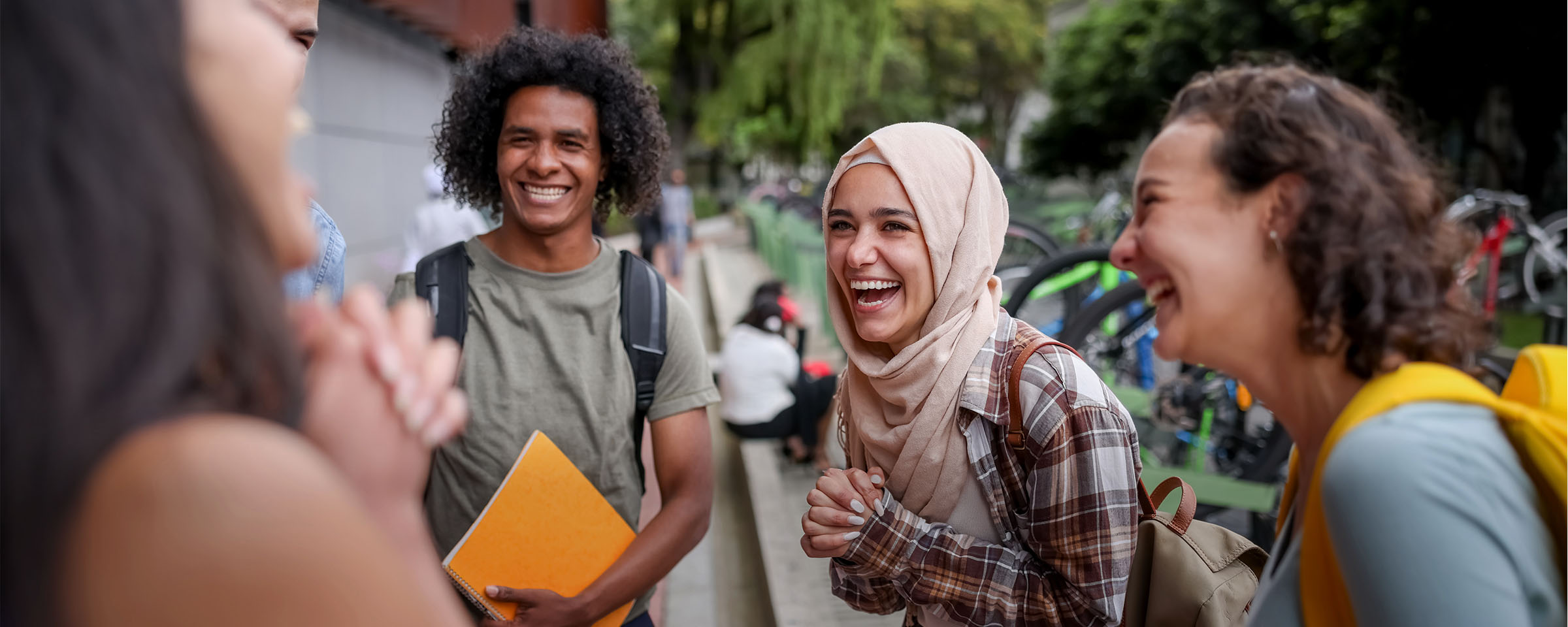 Group of four college students laughing and conversing outdoors