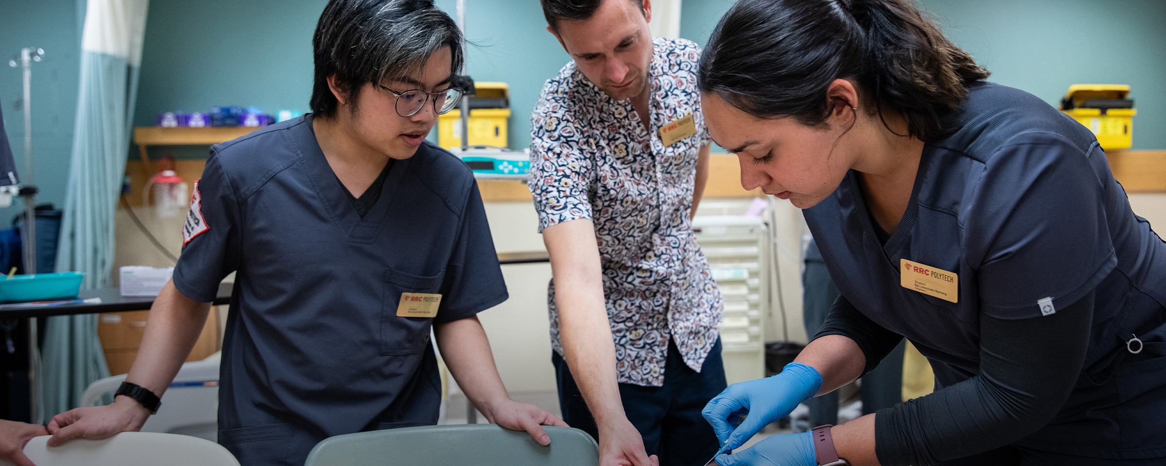 Male nursing instructor showing male and female students how to insert a syringe.