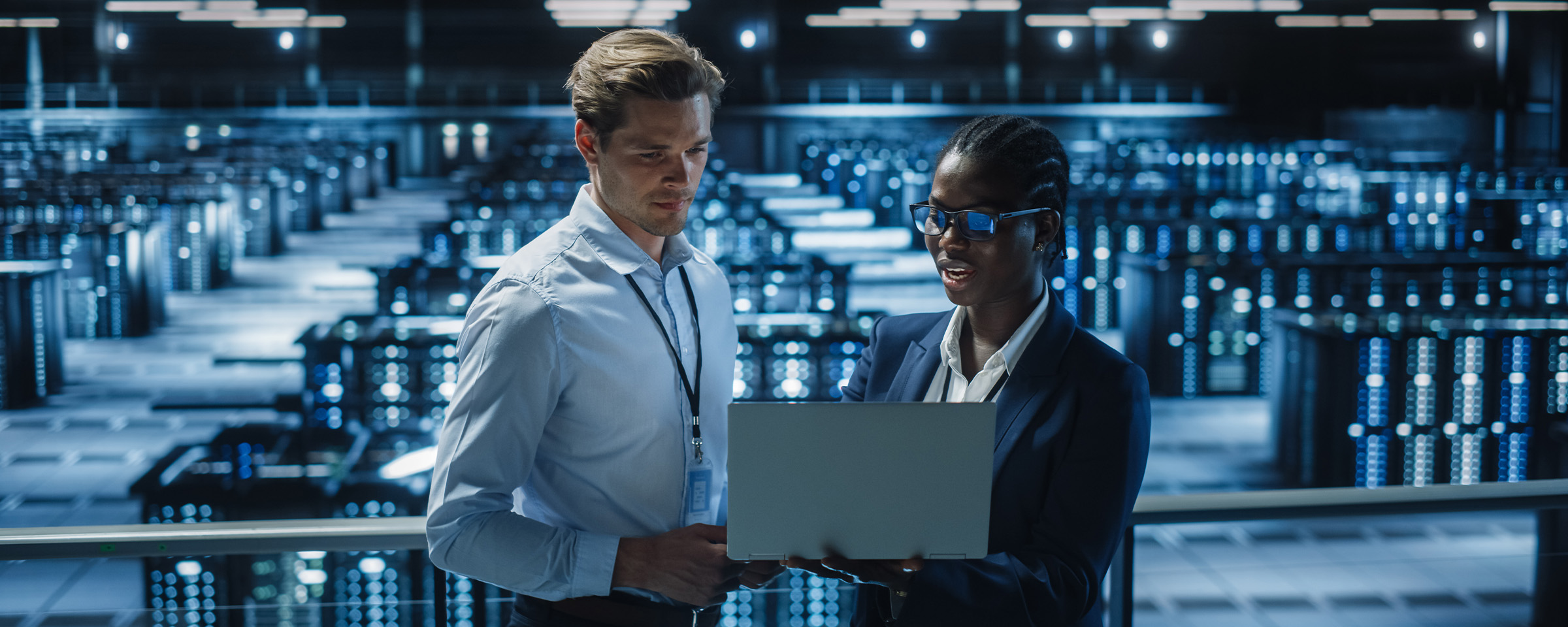 Two people looking at a laptop in a server farm