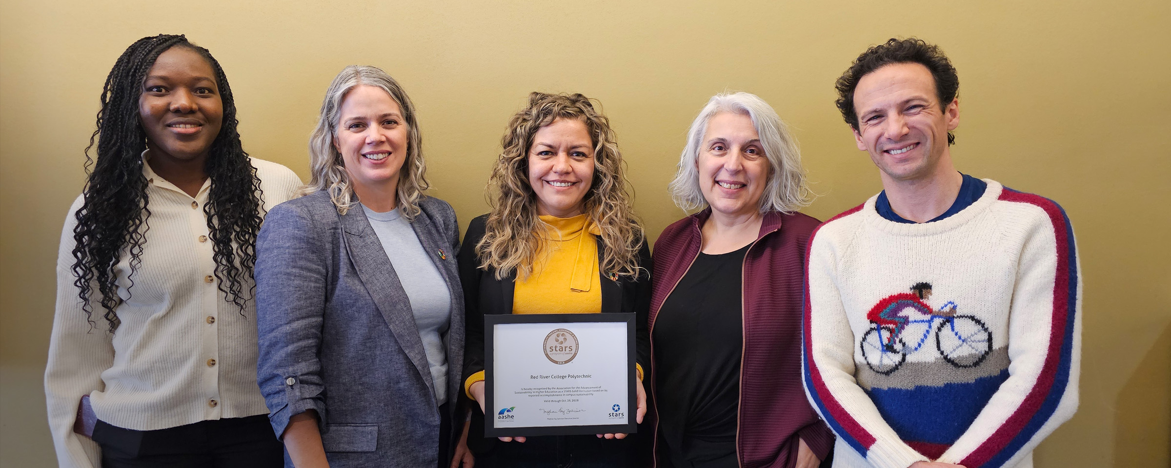 Members of RRC Polytech's Sustainability team standing in a row and displaying the framed certificate denoting their new STARS gold rating.