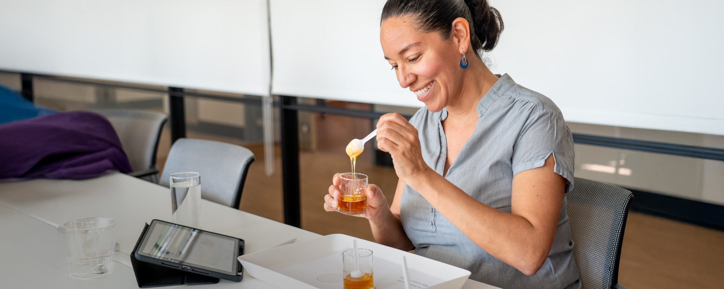 Smiling female researcher spoons honey int a small jar as part of a product assessment trial.